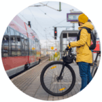 Ein Mann in gelber Regenjacke möchte mit seinem Fahrrad in den Zug einsteigen.