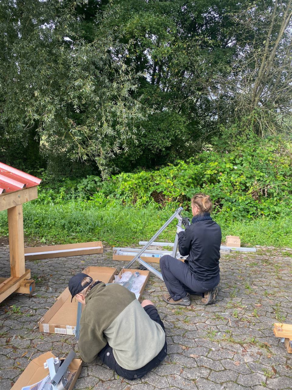 Zwei BalkonScouts setzen gemeinsam das Gestell für ein Balkonkraftwerk zusammen.